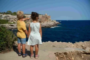 Two Children Standing while Holding Hands at the Ocean - Dismissive Mother