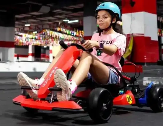 Girl riding a go kart outside