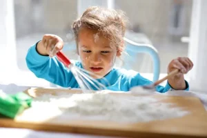 Kid playing with flour- What is Messy Play