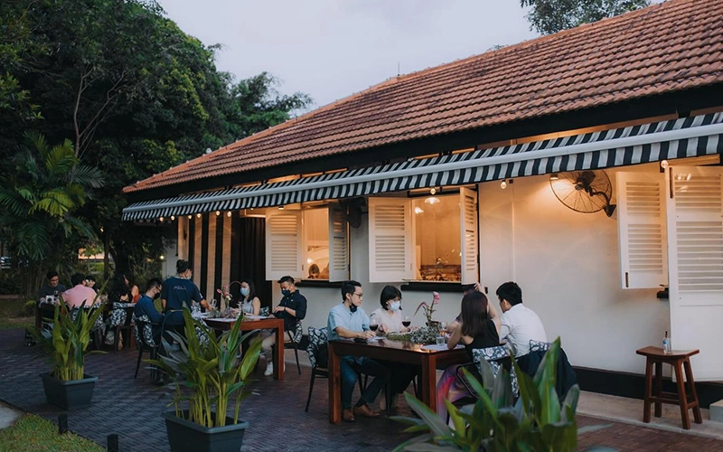 Outdoor dining at a cozy French restaurant with greenery and warm lighting, offering a relaxed atmosphere.