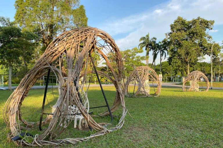 Organic woven art structures on a green lawn, blending with the natural outdoor surroundings.